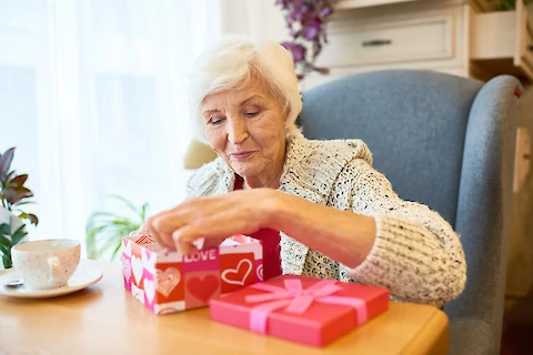 https://www.seniorhelpers.com/site/assets/files/407645/senior_woman_opening_a_gift_on_valentines_day.480x0.webp